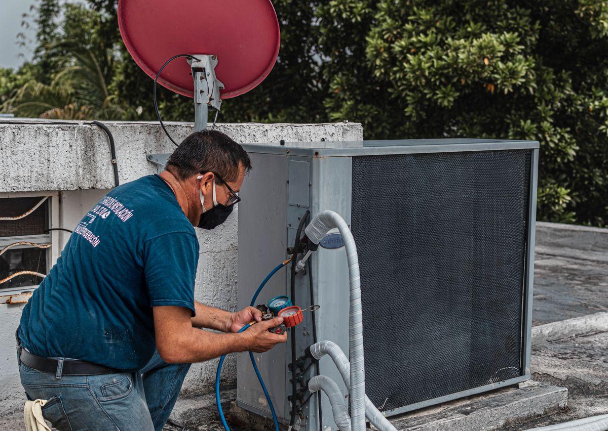 Technician checking outdoor air-conditioning equipment with diagnostic gauges