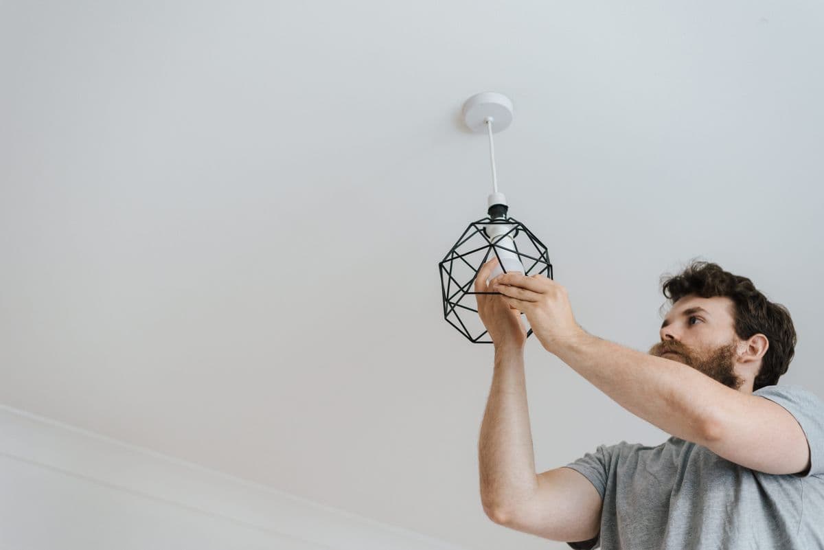 Person fitting a bulb into a ceiling light fixture