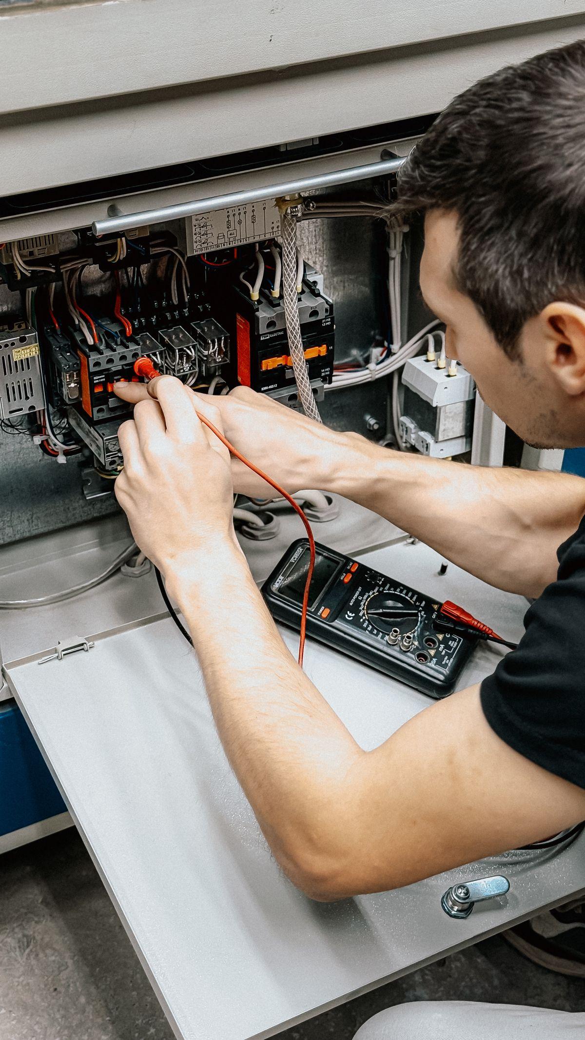 Electrician diagnosing an open electrical panel with a multimeter