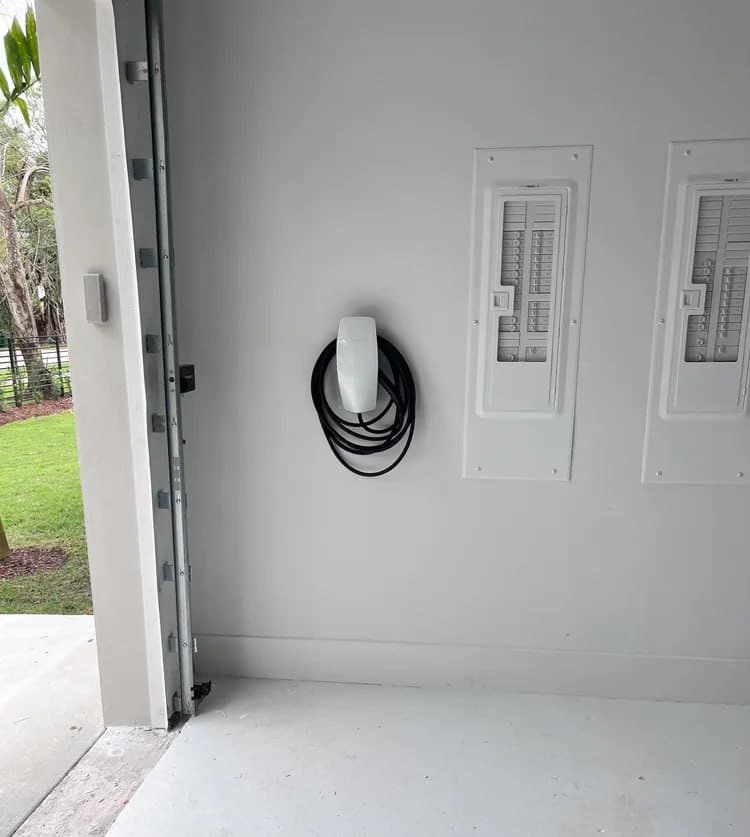 Wall-mounted residential EV charger beside electrical distribution panels