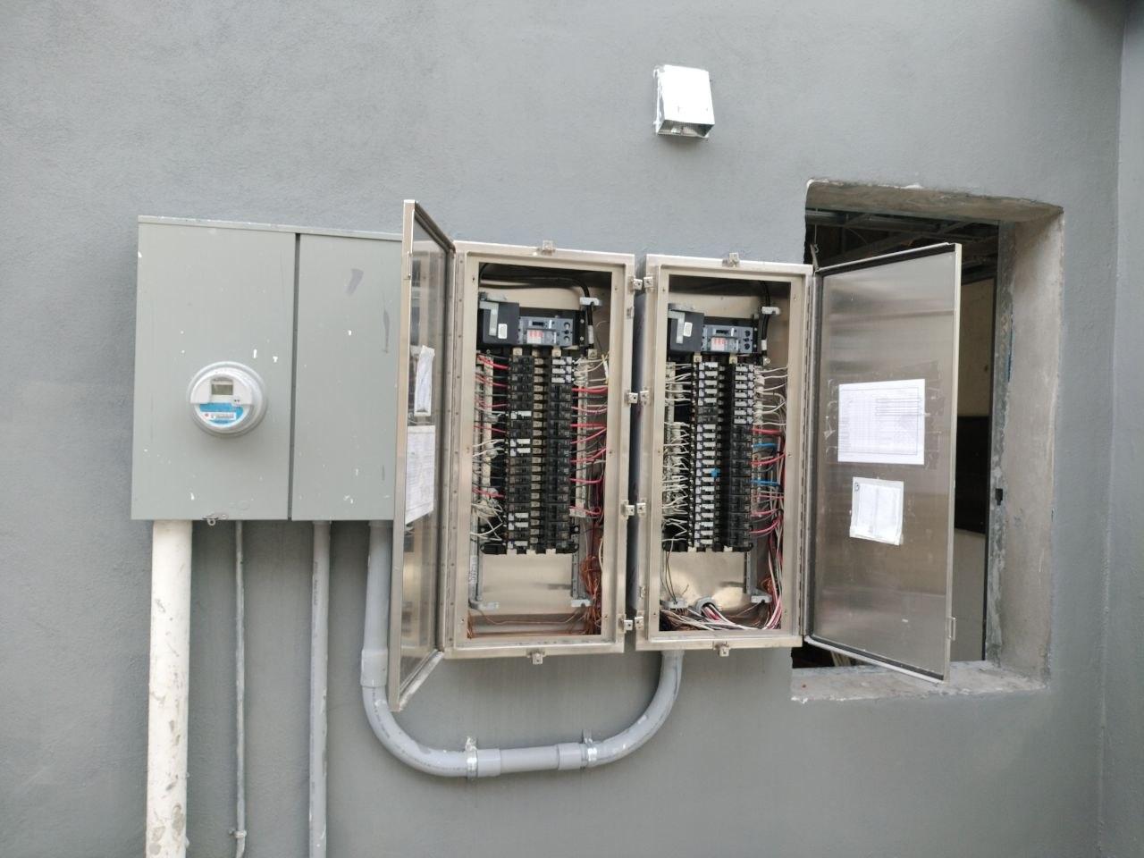 Open electrical distribution panels with breakers and branch-circuit wiring